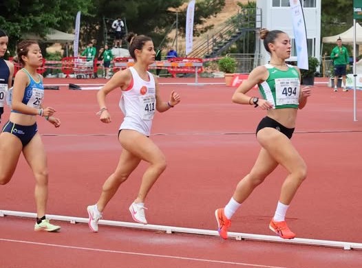 Cristina Munar, estudiante de VIU corriendo una carrera de larga distancia. Viste la camiseta de VIU y está corriendo en una pista en una carrera que forma parte de los CEU de atletismo 2026.