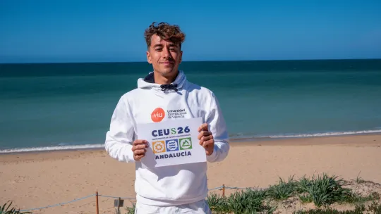 Iker Fernández, estudiante de VIU, con la playa de fondo, sosteniendo el con certificado del CEU Surf 2026 retrato