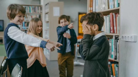 grupo-de-ninos-senalando-y-rienose-de-un-companero-en-una-escena-de-acoso-escolar