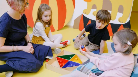 ninos-jugando-a-un-juego-de-bolas-junto-con-una-profesora-desarrollando-la-autonomia-infantil