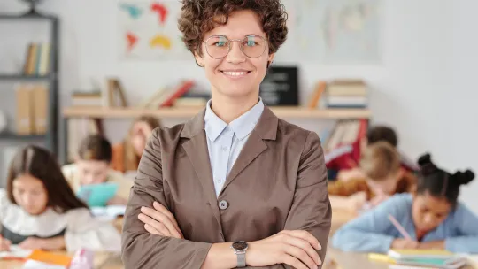 una-profesora-posa-con-los-brazos-cruzados-mostrando-habilidades-blandas-como-paciencia-empatía-y-comunicación-en-el-aula