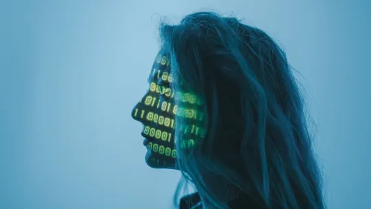 Perfil con proyección de datos aplicados a la ingeniería en organización industrial Perfil lateral en tono azul de una mujer sobre el cual se proyectan códigos binarios y datos numéricos en verde, ilustrando la intersección entre tecnología e ingeniería en organización industrial.