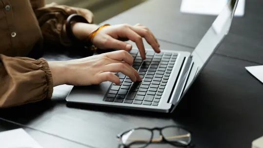 persona-escribiendo-en-un-portatil-simbolizando-la-ley-de-emprendimiento-ley-28-2022