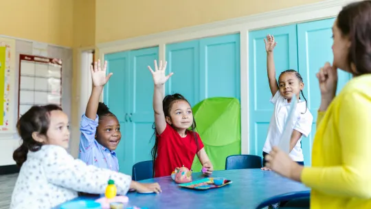 grupo-de-ninos-en-clase-levantando-la-mano-para-participar-en-una-sesion-de-psicologia-educativa