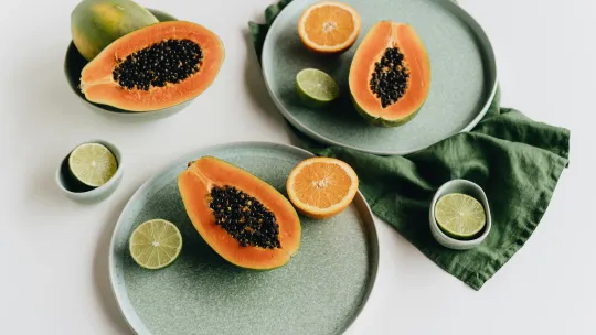 rodajas-de-papaya-naranja-y-limon-sobre-platos-verdes-como-representacion-de-una-alimentacion-balanceada-para-la-salud-nutricional