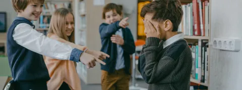 grupo-de-ninos-senalando-y-rienose-de-un-companero-en-una-escena-de-acoso-escolar