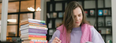 mujer-estudiando-en-una-biblioteca-con-libros-sobre-las-asignaturas-de-psicologia