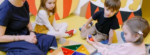 ninos-jugando-a-un-juego-de-bolas-junto-con-una-profesora-desarrollando-la-autonomia-infantil