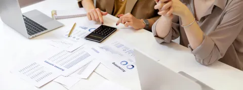 dos-mujeres-trabajando-en-una-base-de-datos-relacional-con-ordenadores-informes-y-calculadora