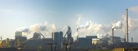 chimeneas-de-una-industria-lanzando-emisiones-visibles-simbolo-de-como-afecta-el-cambio-climatico-al-ser-humano