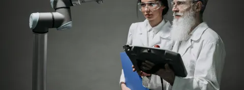 dos-expertos-en-ia-para-empresas-con-bata-blanca-operando-un-brazo-robotico-industrial