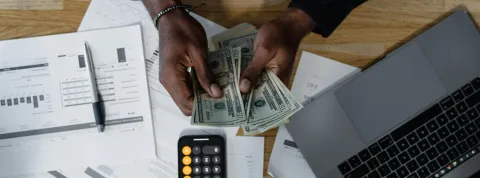 persona-contando-dinero-sobre-documentos-financieros-como-parte-de-la-gestion-financiera-en-colombia