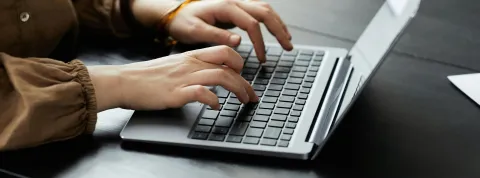 persona-escribiendo-en-un-portatil-simbolizando-la-ley-de-emprendimiento-ley-28-2022