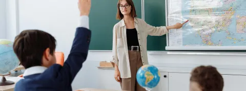 aula-con-maestra-de-educacion-infantil-senalando-un-mapa-mientras-un-nino-participa