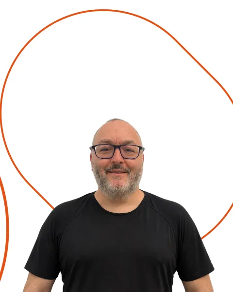 Retrato de Antonio Gala estudiante de VIU, recortado sobre fondo blanco con formas geométricas ovaladas en naranja. Antonio viste camiseta negra y lleva gafas.