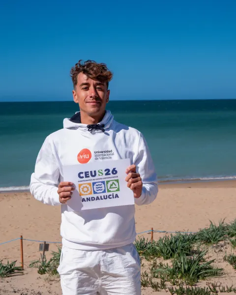 Iker Fernández, estudiante de VIU, con la playa de fondo, sosteniendo el con certificado del CEU Surf 2026 retrato