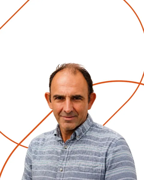Retrato del experto de VIU Raúl Reyero. Viste camisa a rayas azul y su retrato está recortado sobre un fondo blanco con formas geométricas naranjas