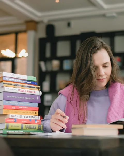 mujer-estudiando-en-una-biblioteca-con-libros-sobre-las-asignaturas-de-psicologia