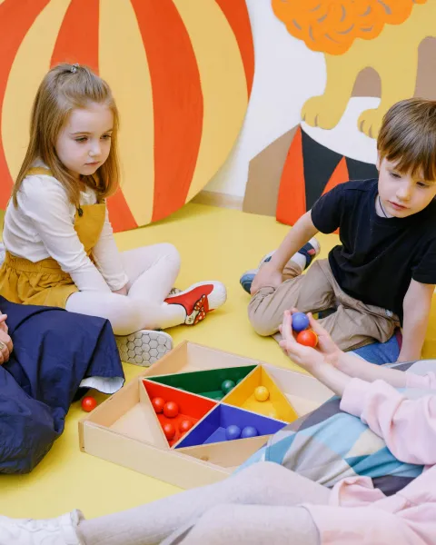 ninos-jugando-a-un-juego-de-bolas-junto-con-una-profesora-desarrollando-la-autonomia-infantil