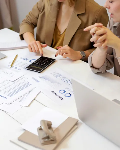 dos-mujeres-trabajando-en-una-base-de-datos-relacional-con-ordenadores-informes-y-calculadora