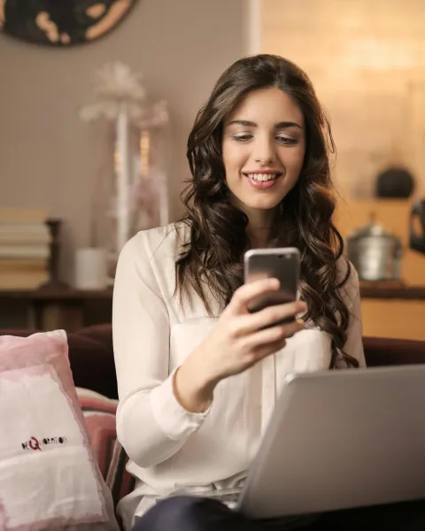 mujer-sentada-en-un-sofa-con-el-ordenador-en-las-rodillas-y-haciendo-live-shopping-con-el-movil