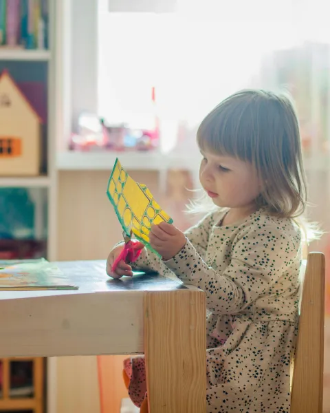 nina-pequena-en-un-salon-de-clases-recortando-papel-como-parte-del-desarrollo-infantil