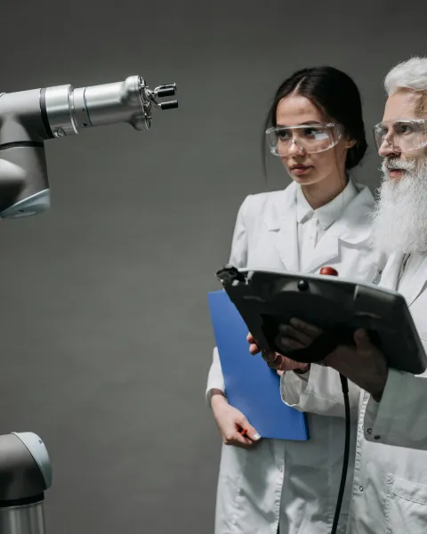dos-expertos-en-ia-para-empresas-con-bata-blanca-operando-un-brazo-robotico-industrial