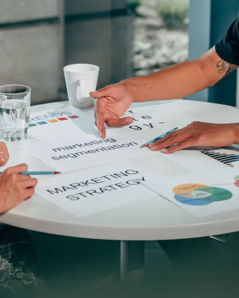 Dos profesionales reunidos alrededor de una mesa blanca analizando documentos sobre estrategias y segmentación, representando el análisis para elegir herramientas de marketing automation.