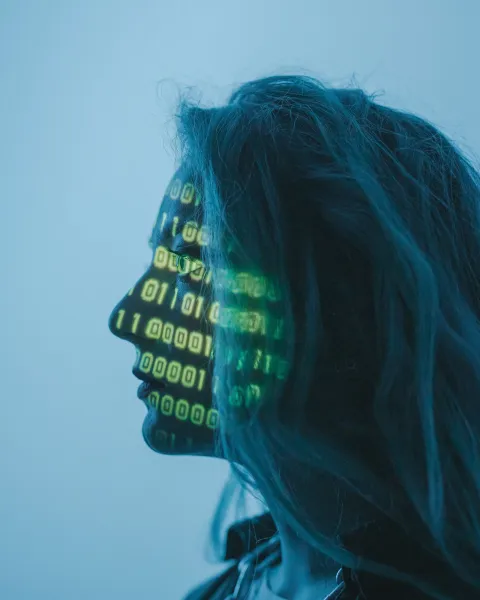 Perfil lateral en tono azul de una mujer sobre el cual se proyectan códigos binarios y datos numéricos en verde, ilustrando la intersección entre tecnología e ingeniería en organización industrial.