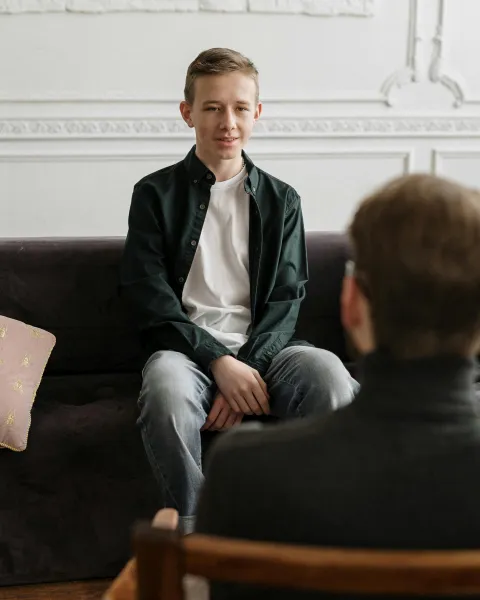 un-joven-en-una-sesion-con-un-neuropsicologo-sentado-en-un-sofa-gris