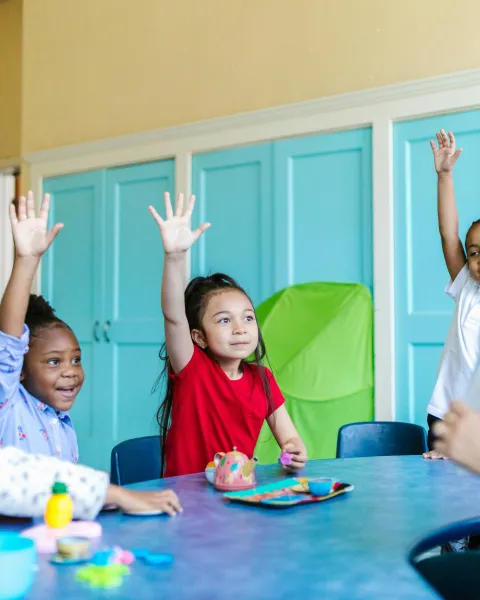 grupo-de-ninos-en-clase-levantando-la-mano-para-participar-en-una-sesion-de-psicologia-educativa