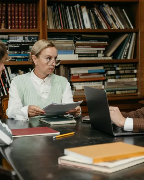 docente-con-gafas-orientando-a-dos-estudiantes-sobre-las-salidas-del-master-de-profesorado-en-una-biblioteca