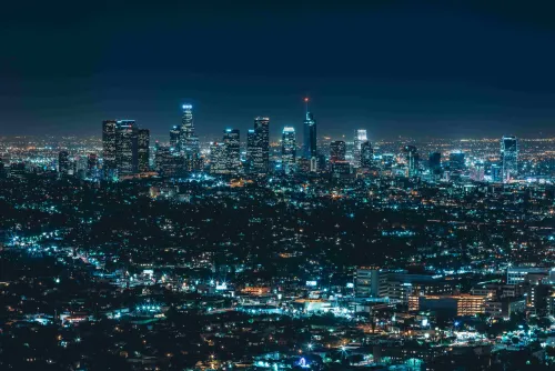 Foto panorámica de la ciudad de Los Angeles de noche. Muestra un paisaje de edificios altos iluminados por luces eléctricas.