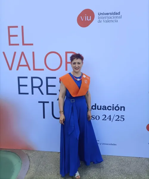 Retrato de Karina Martínez, alumni VIU, el día de su graduación en la Universidad Internacional de Valencia. Lleva un vestido azul largo y la beca naranja de la universidad.