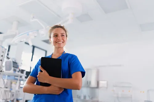 Profesional de enfermería gestionando el triaje hospitalario Una enfermera con uniforme azul sostiene una tableta digital en una unidad de triaje en enfermería hospitalaria.